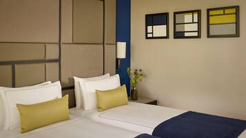 A hotel room with a large bed, two bedside tables, a nightstand, a lamp, and three framed artworks on the wall.