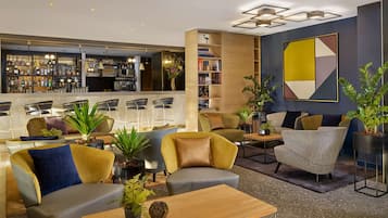 A modern lounge area with seating, a bar, and a bookshelf.