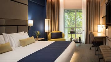 A hotel room with a large bed, a desk, a chair, and a TV.