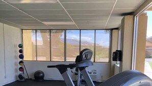 Una palestra con tapis roulant, cyclette e palle da ginnastica.
