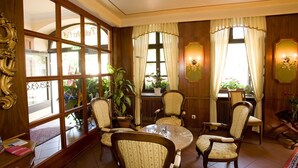A room with a large window, wooden paneled walls, a round table, and several upholstered chairs. - City Partner Hotel Holländer Hof (Heidelberg)