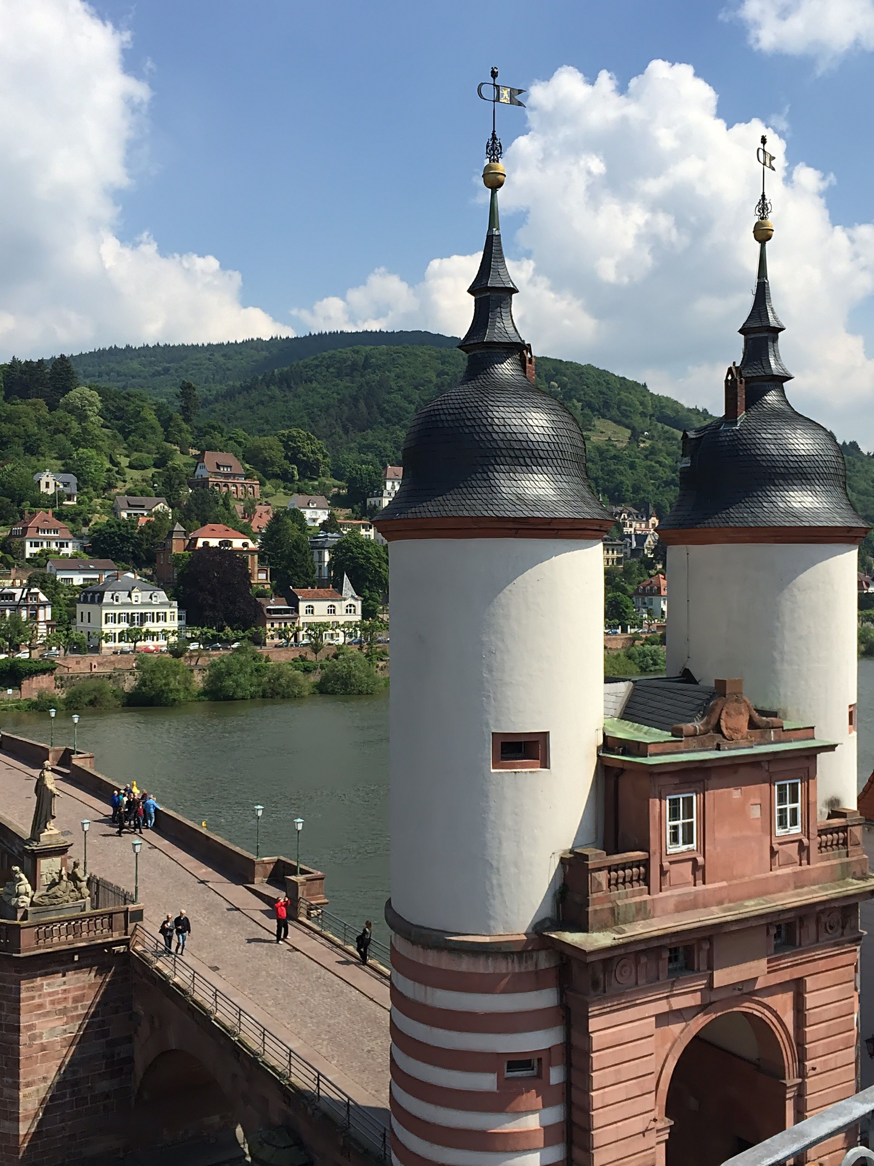 A historic building with two prominent towers, a bridge, and a river in the background.