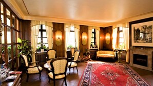 A traditional room with wooden paneling, a red patterned rug, and multiple seating areas with upholstered chairs. - City Partner Hotel Holländer Hof (Heidelberg)