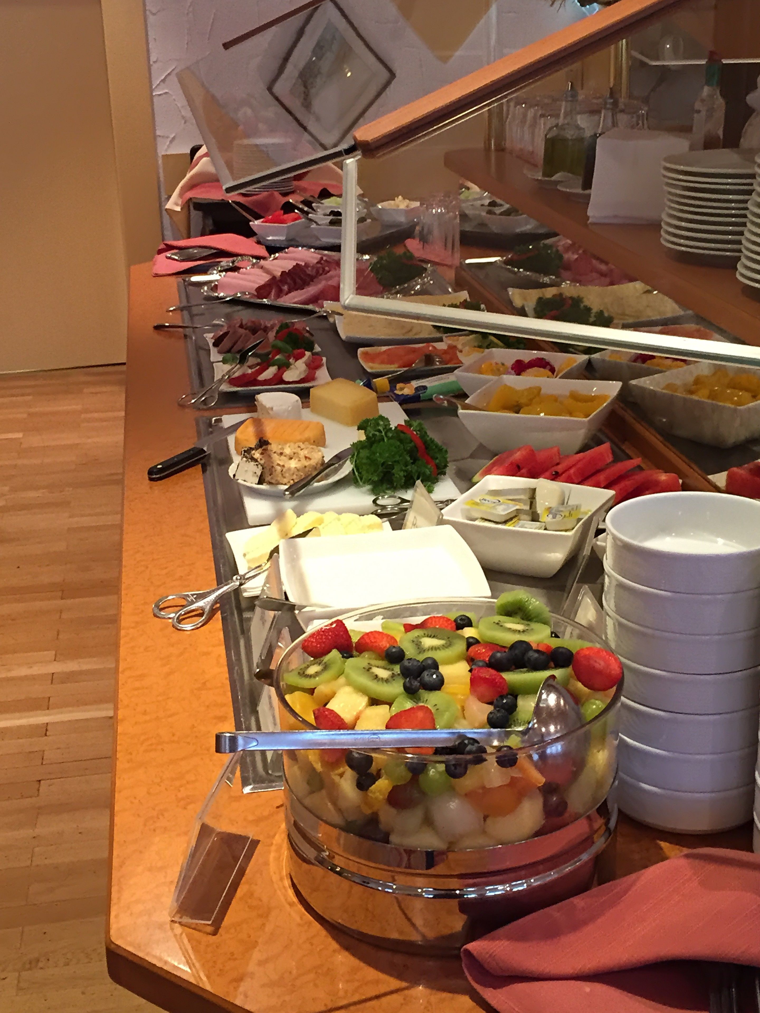 A buffet with various food items including fruits, cheeses, and meats.