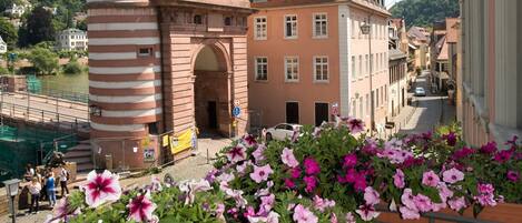 A historic building with two towers, a central archway, and a flower-covered balcony.