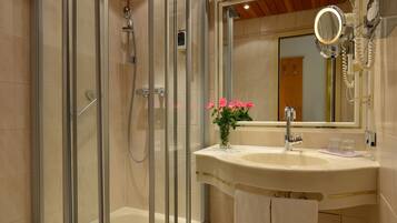 Une salle de bain avec une douche à parois de verre, un lavabo avec un miroir et des toilettes.