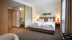 A hotel room with a large bed, a chair, and a bathroom visible through an open door. - Hotel am Jakobsmarkt (Nuremberg)