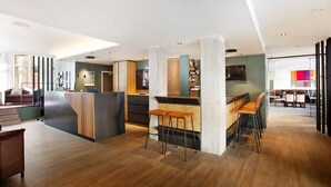 A modern bar area with wooden flooring, bar stools, and a counter. - Hotel am Jakobsmarkt (Nuremberg)