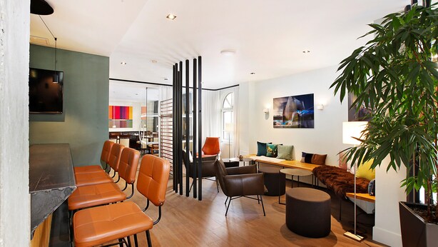 A modern interior with a dining area, seating, and a large plant. - Hotel am Jakobsmarkt (Nuremberg)