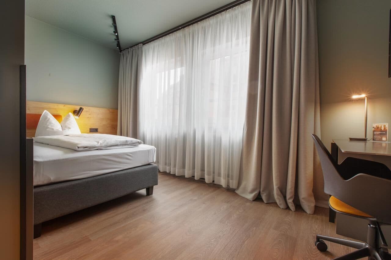 A hotel room with a bed, a desk, and a chair.