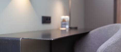 Una habitación moderna y minimalista con un escritorio elegante de color oscuro y una cómoda silla gris.