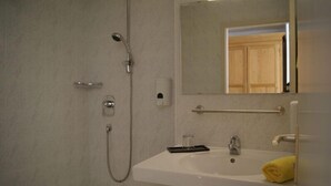 A bathroom with a bathtub, a sink, a mirror, and a shower. - Hotel Freihof (Stuttgart)