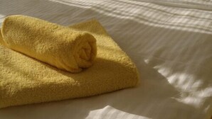 A neatly folded yellow towel on a bed with white bedding. - Hotel Freihof (Stuttgart)