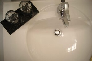 A white sink with a chrome faucet and a black tray holding two glasses. - Hotel Freihof (Stuttgart)
