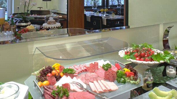 Un bufé con diversos alimentos, entre ellos carnes, ensaladas y frutas.