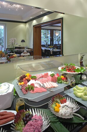 Un bufé con diversos alimentos, entre ellos carnes, ensaladas y frutas.