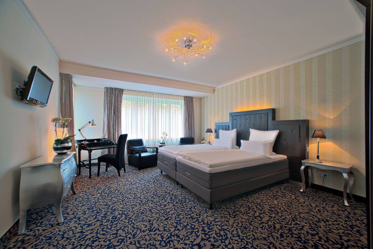 A hotel room with a bed, desk, chair, and a television.