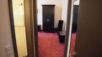 A hallway with a red patterned carpet, a black chair, and a black wardrobe.