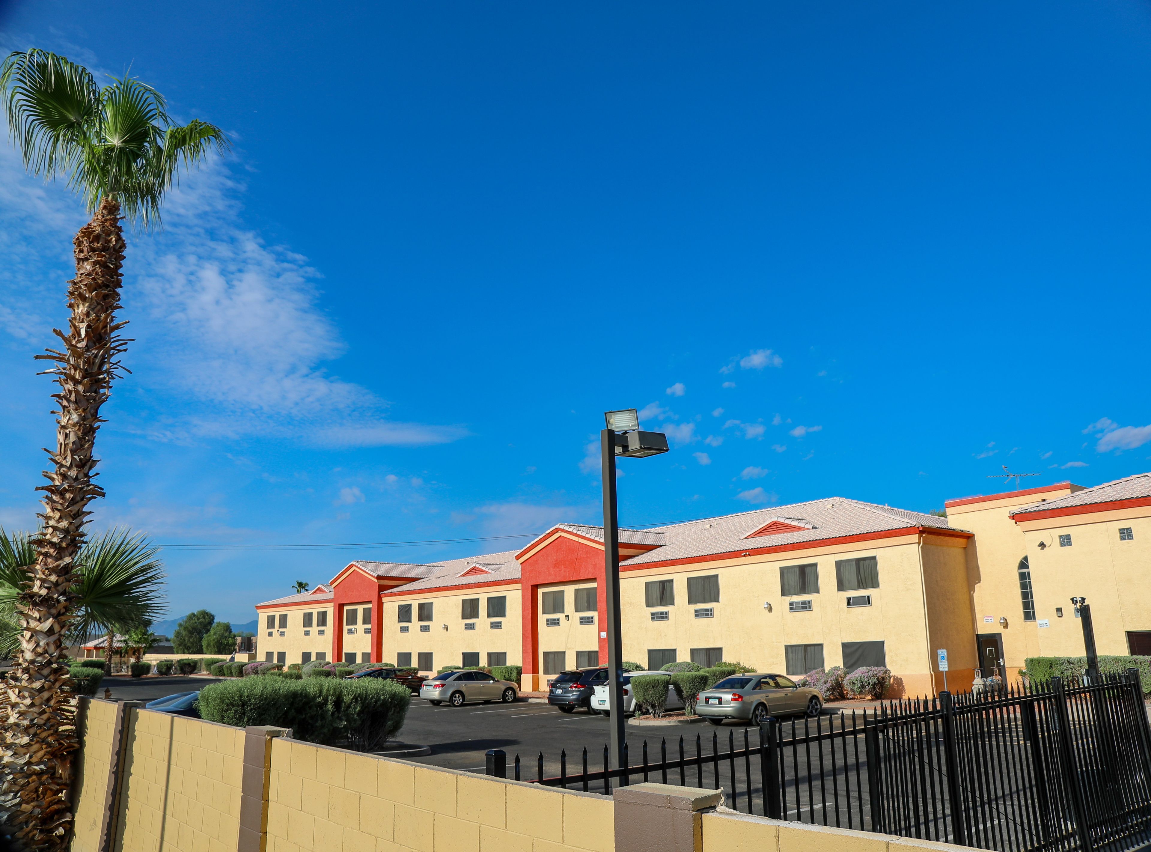 A hotel with multiple buildings, a parking lot, and a palm tree.