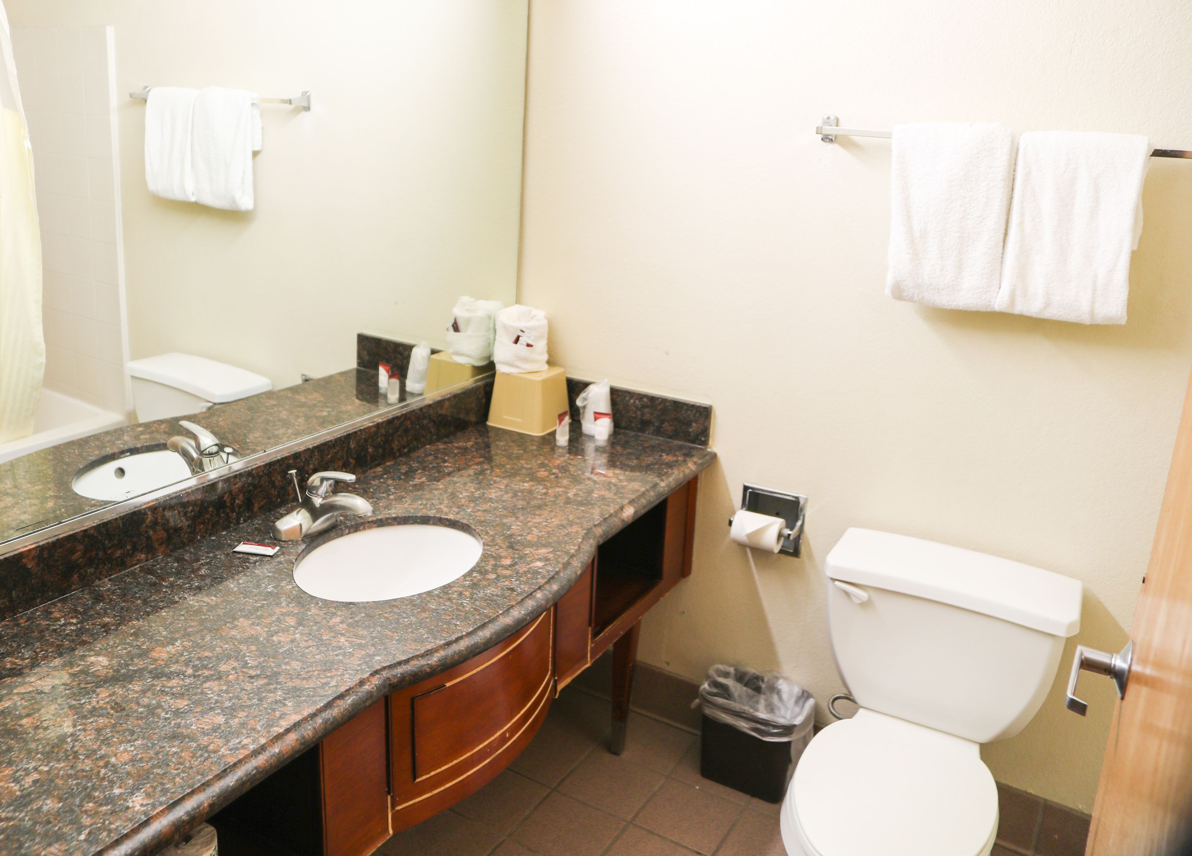 Une salle de bain avec deux lavabos, des toilettes et une poubelle.