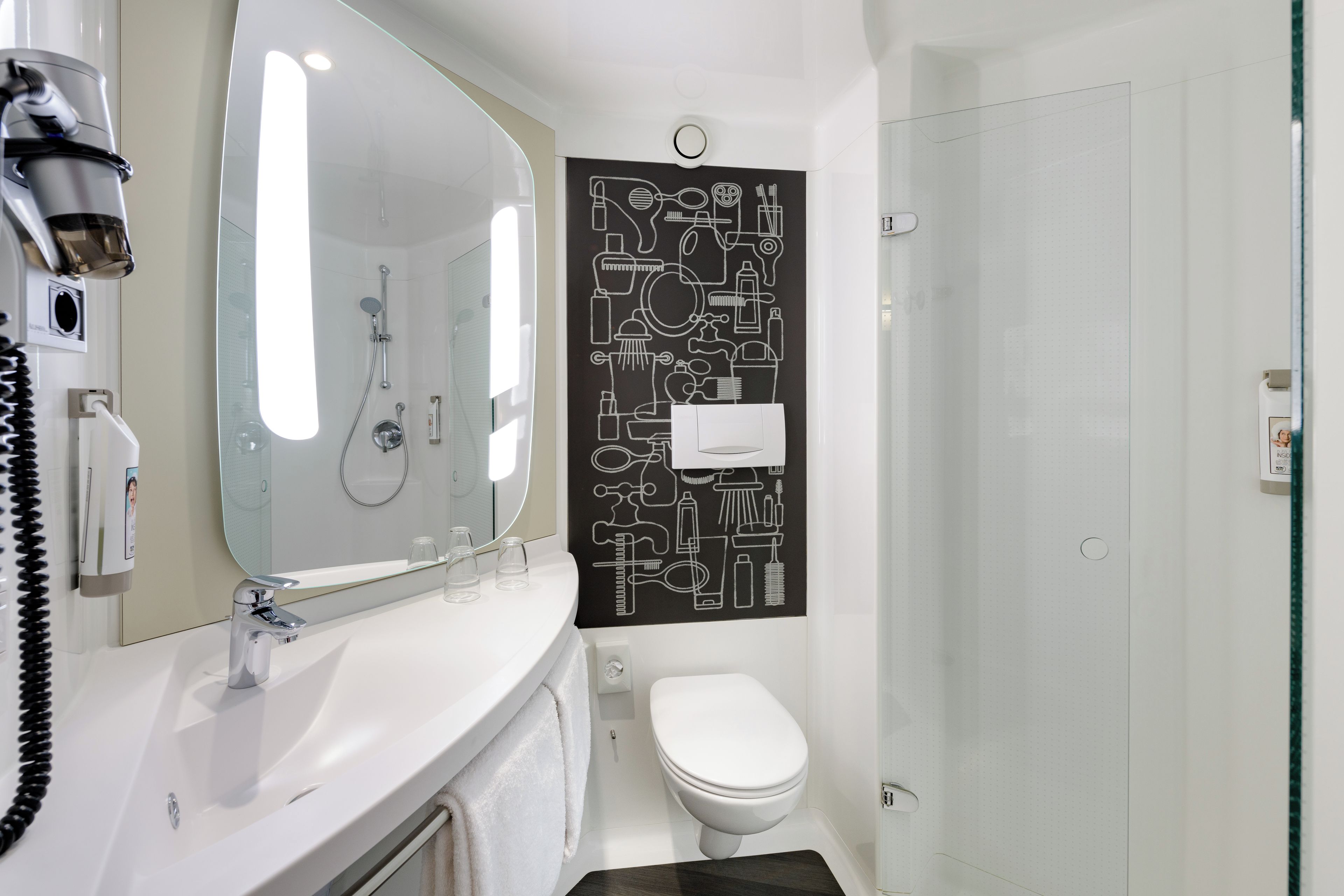 A modern bathroom with a large mirror, a toilet, and a shower.