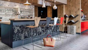 A modern bar area with a black and white patterned wall, multiple bar stools, and pendant lighting. - ibis Muenster City (Münster)