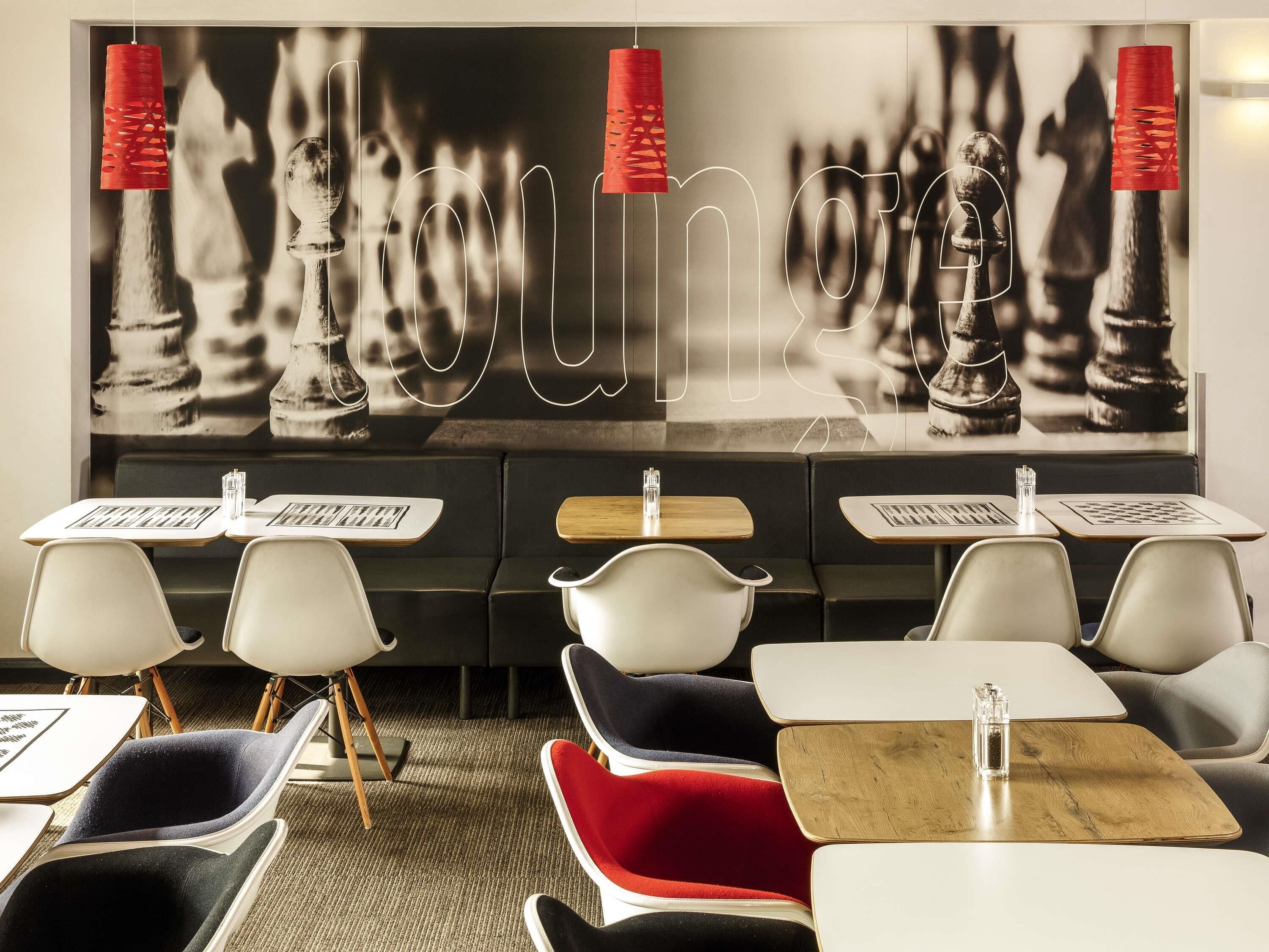 Een restaurant met schaakthema, met tafels, stoelen en een grote muurschildering van een schaakbord.