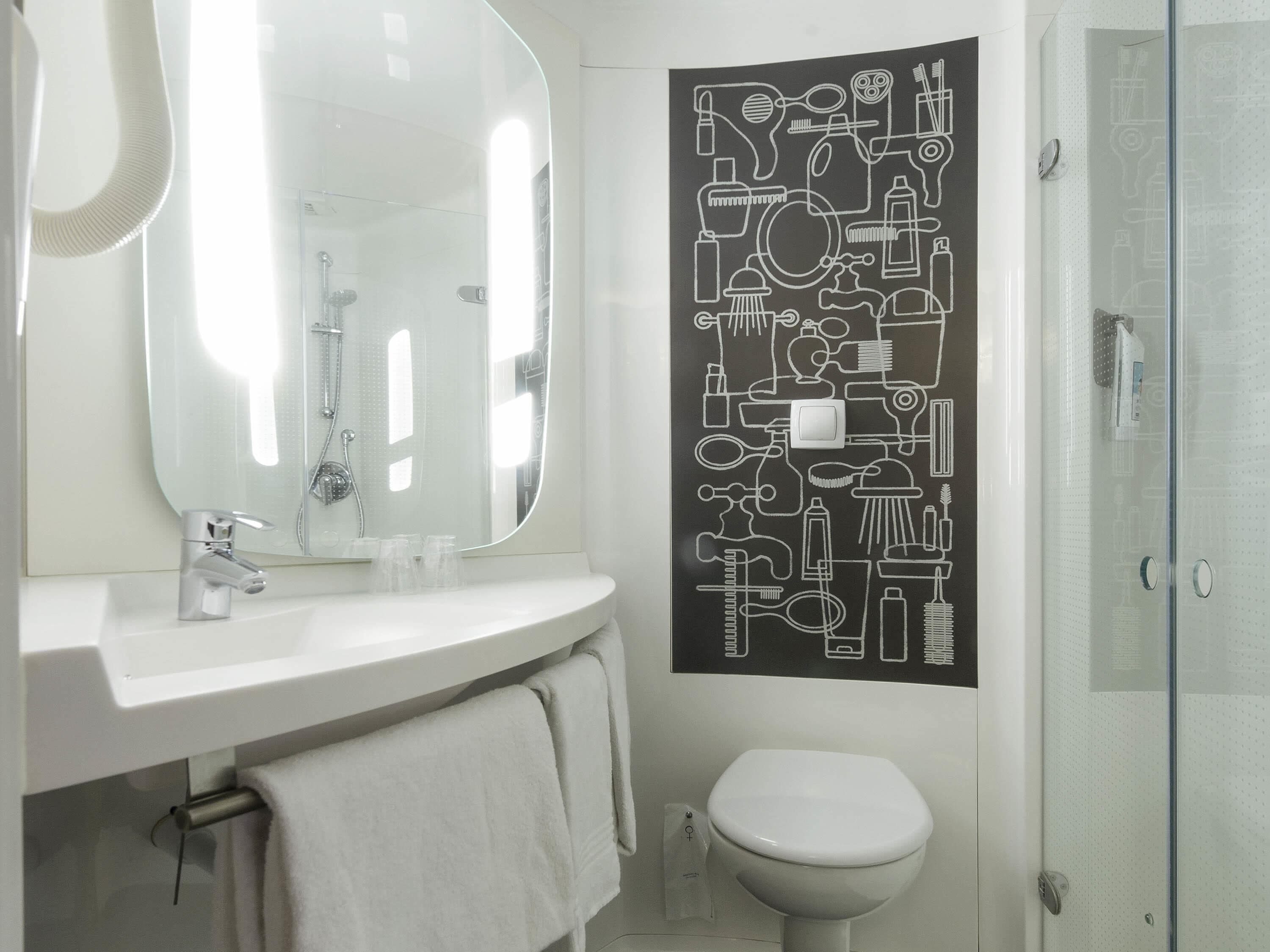 A modern bathroom with a white sink, mirror, and toilet.