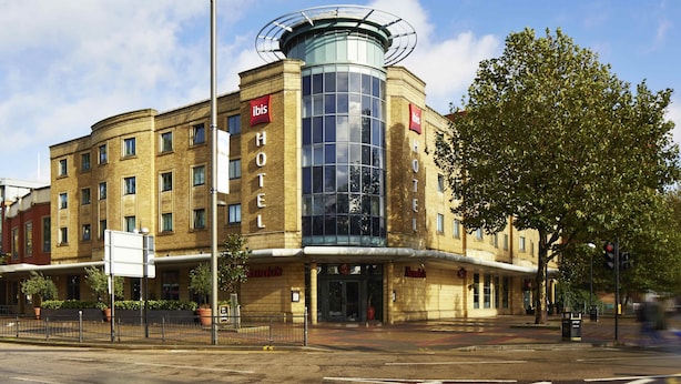 A hotel with a modern glass facade, a prominent circular skylight, and a classic brick exterior. - ibis London Stratford (London)
