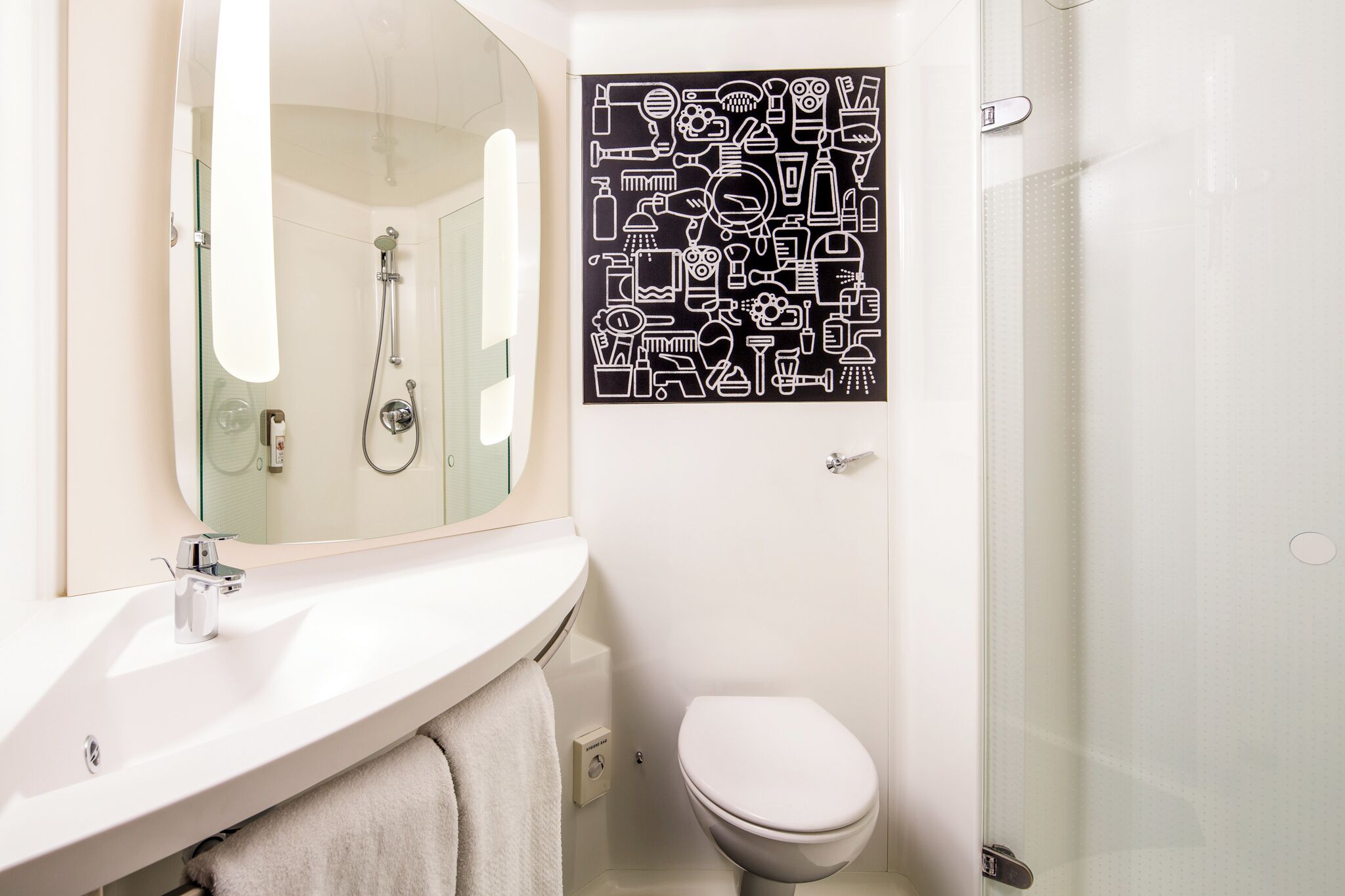 A bathroom with a white sink, mirror, toilet, and shower.