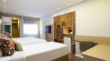 A hotel room with two beds, a TV, a desk, and a cityscape view.