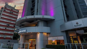 A modern hotel with a prominent entrance, a sign for a restaurant, and a staircase leading to the entrance.