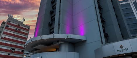 A modern hotel with a prominent entrance, a sign for a restaurant, and a staircase leading to the entrance.