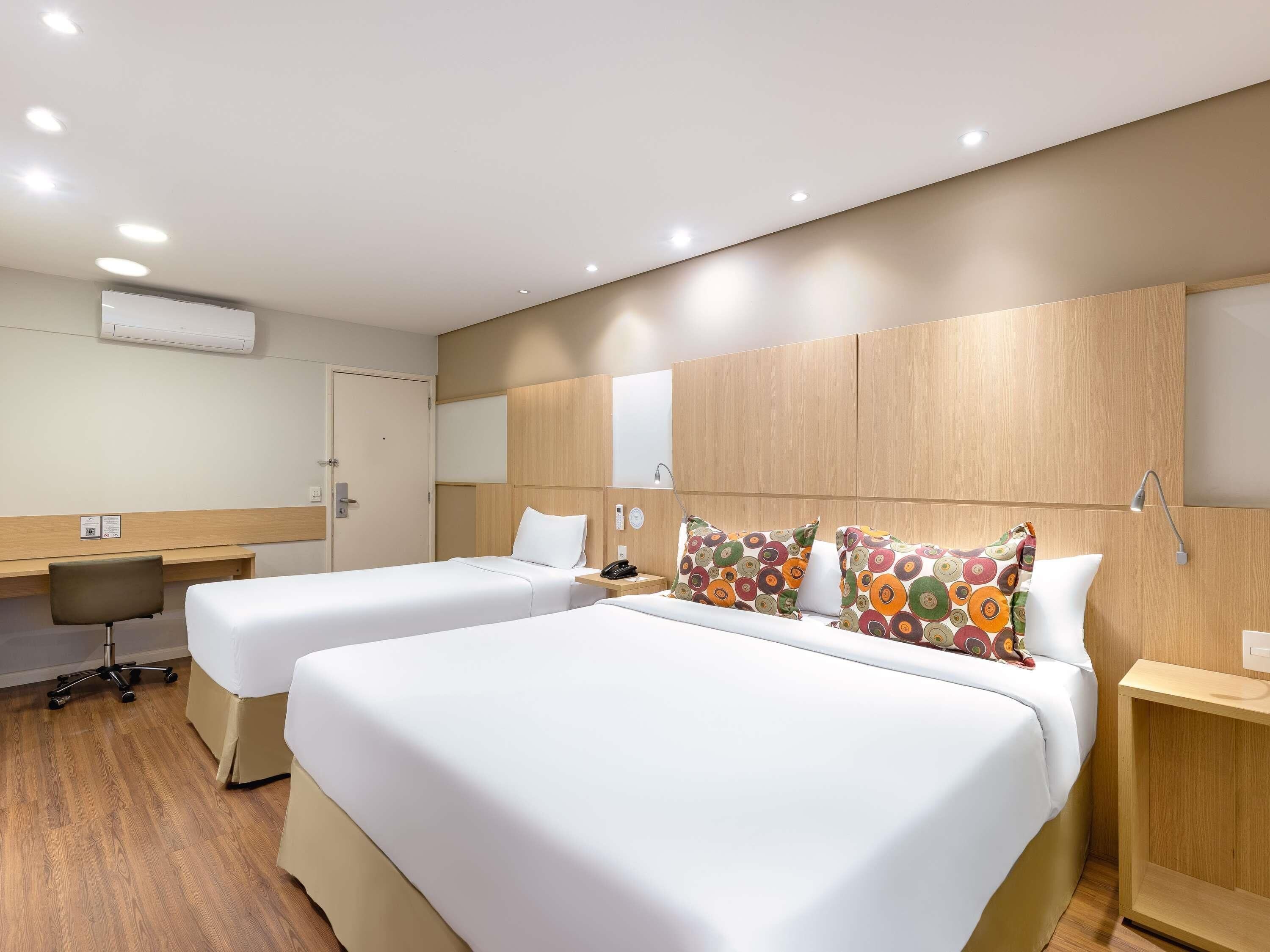 Habitación de hotel con dos camas, un escritorio y una silla.