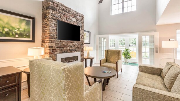 A spacious living room with a stone fireplace, a flat-screen TV, and comfortable seating. - Quality Inn Gallatin - Nashville Metro (Gallatin)