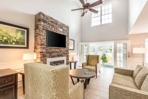 A spacious living room with a stone fireplace, a flat-screen TV, and comfortable seating.