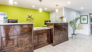 A hotel reception desk with a green wall, wooden paneling, and a sign that reads "Quality Inn." - Quality Inn Gallatin - Nashville Metro (Gallatin)