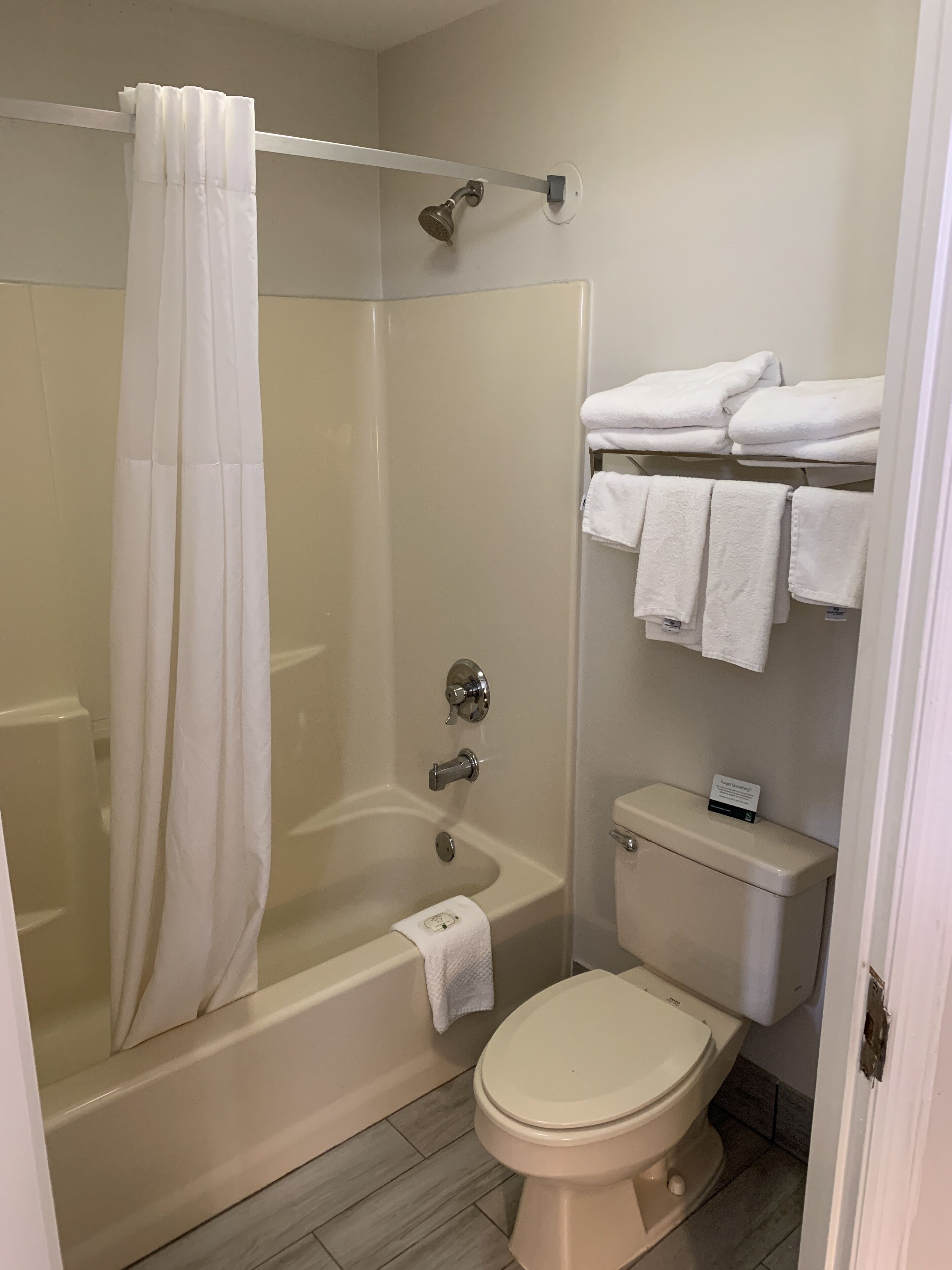 A bathroom with a glass-enclosed shower, a white toilet, and a towel rack with folded towels.