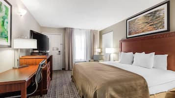 A hotel room with a bed, a desk with a chair, a television, and a painting on the wall.