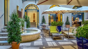 An outdoor seating area with umbrellas, a fountain, and potted plants. - UNA Hotels Empire Roma (Rome)