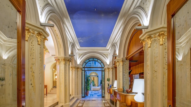 A grand hallway with ornate columns, a starry ceiling, and a view into a luxurious room. - UNA Hotels Empire Roma (Rome)