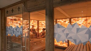 A sauna with wooden benches and a glass partition with geometric patterns. - Hotel Alex (Naters)