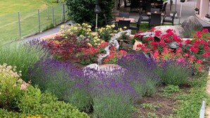 A garden with various flowers and plants, a pathway, and outdoor seating. - Hotel Alex (Naters)