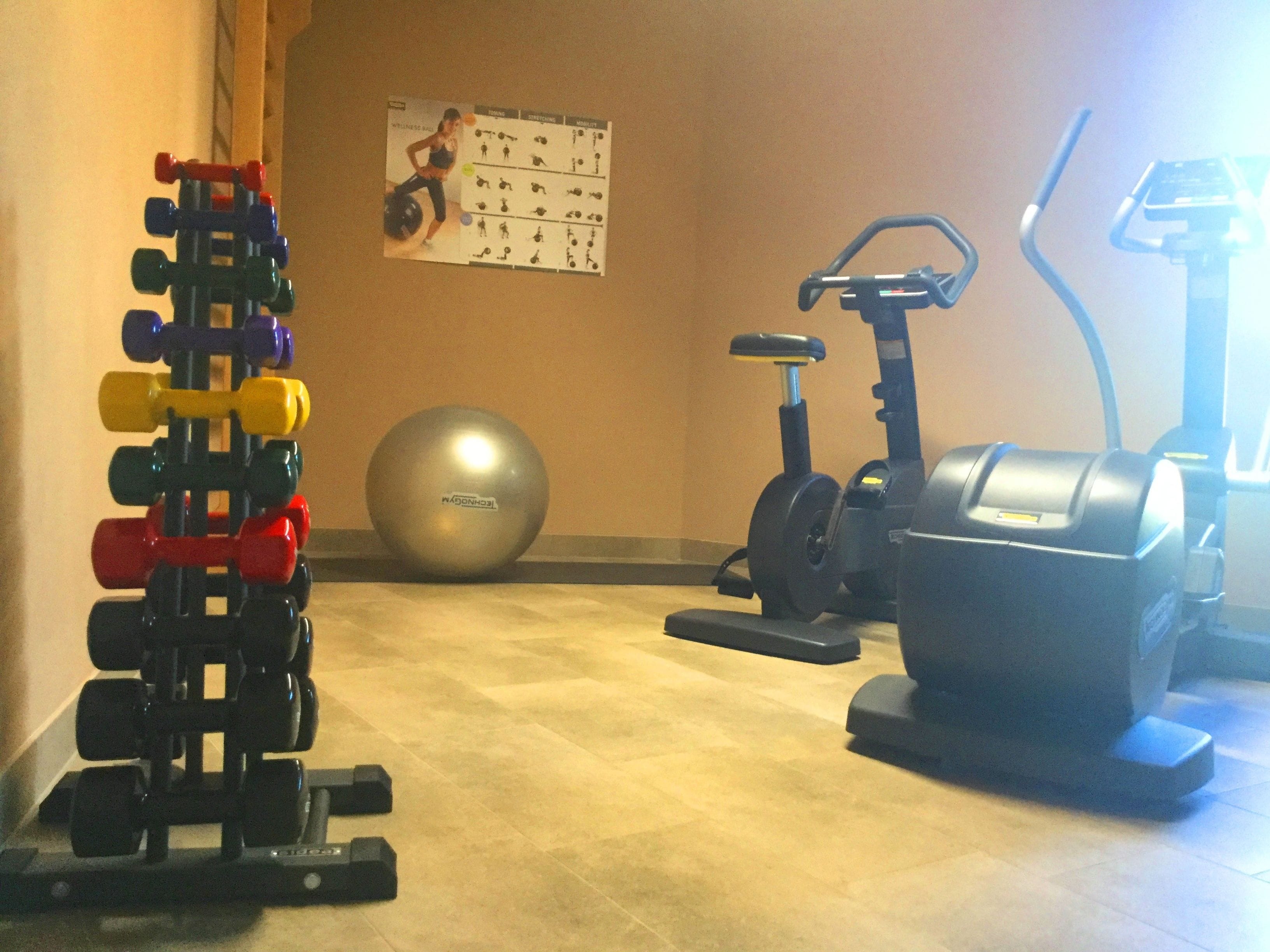 A home gym with a weight rack, exercise ball, and stationary bikes.
