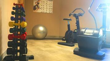 A home gym with a weight rack, exercise ball, and stationary bikes.
