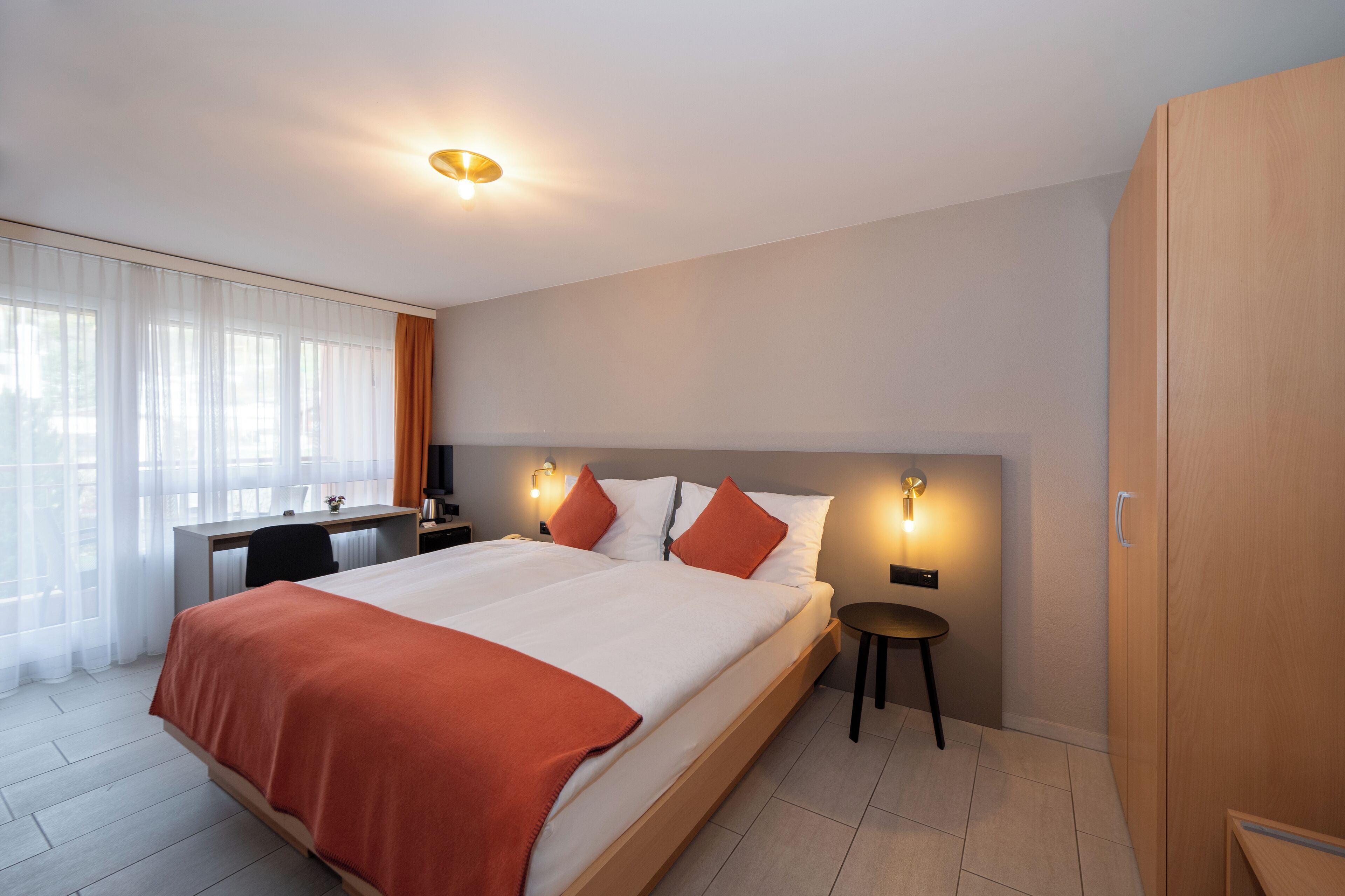 Et moderne hotelværelse med en stor seng, et skrivebord og et garderobeskab.