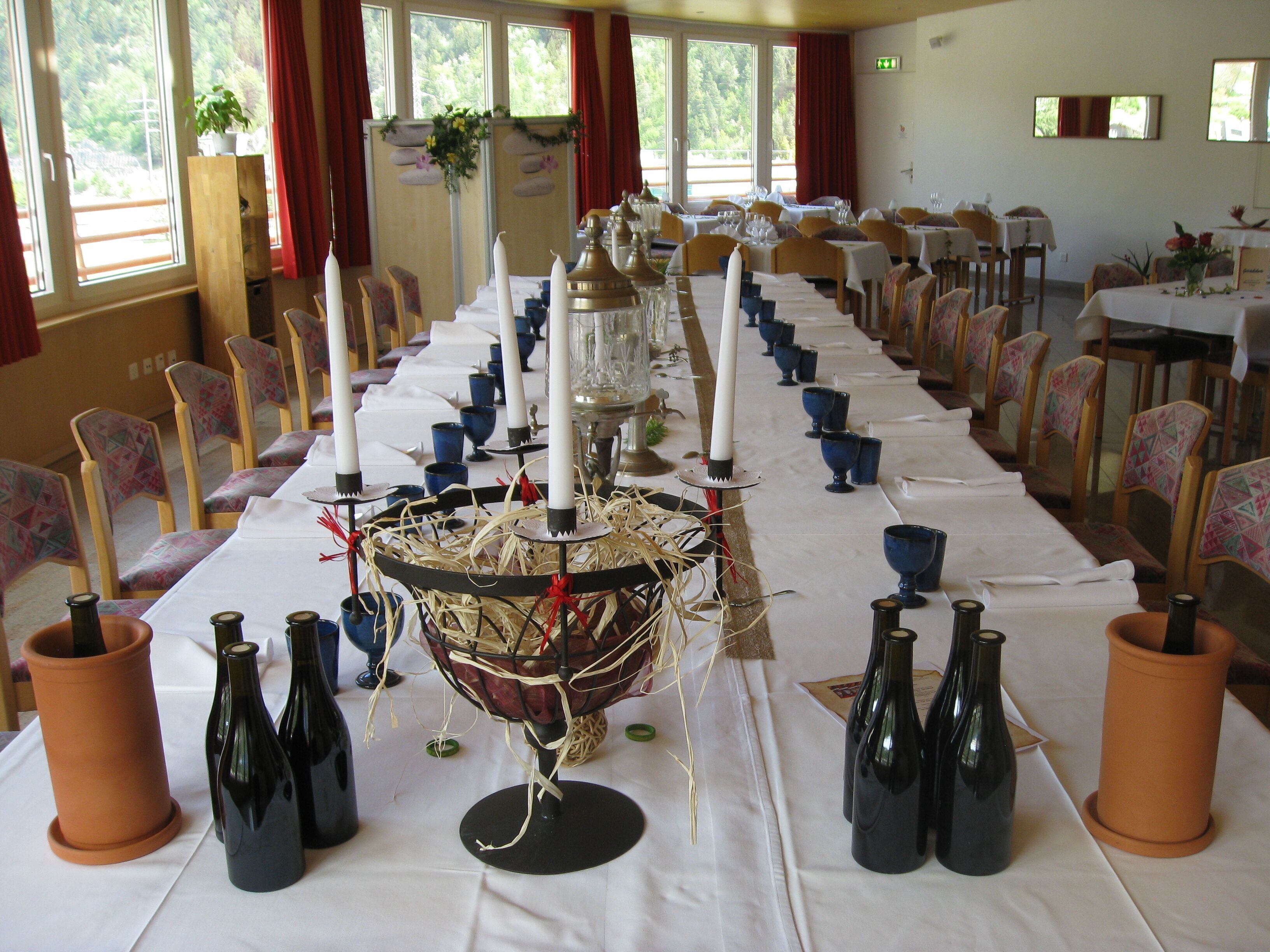 A long dining table with multiple candles, blue glassware, and wine bottles.