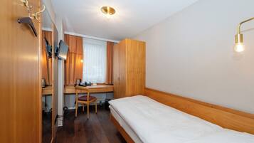 A compact room with a wooden bed, a desk with a chair, and a wardrobe.