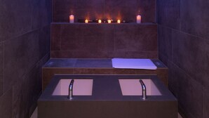 A modern bathroom with a rectangular bathtub, a built-in sink, and a shelf with candles. - Hotel Alex (Naters)