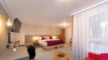 A modern hotel room with a bed, desk, chair, and a small table.